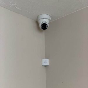 Indoor dome security camera in a ceiling corner with an alarm motion sensor below