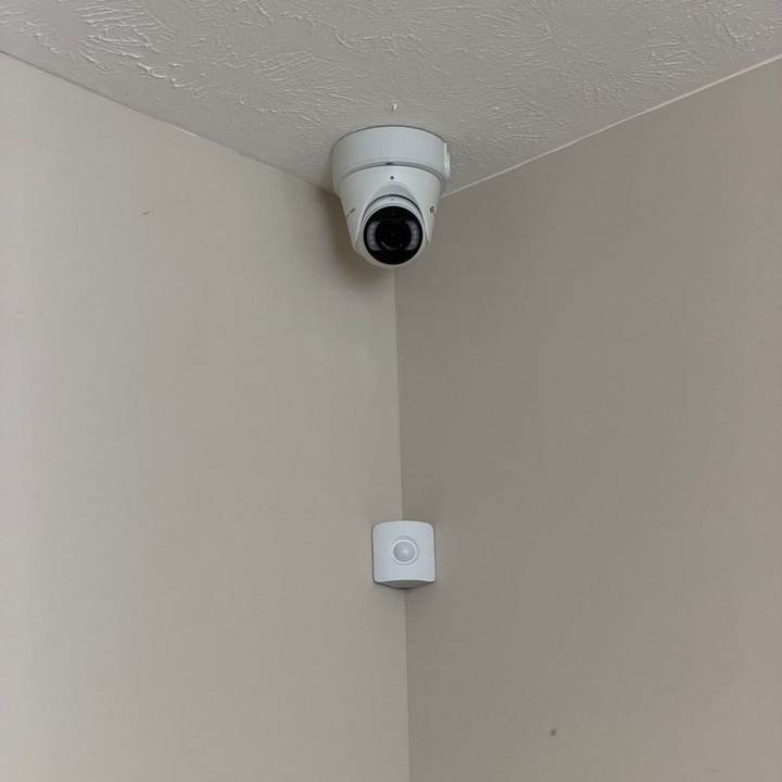 Indoor dome security camera in a ceiling corner with an alarm motion sensor below